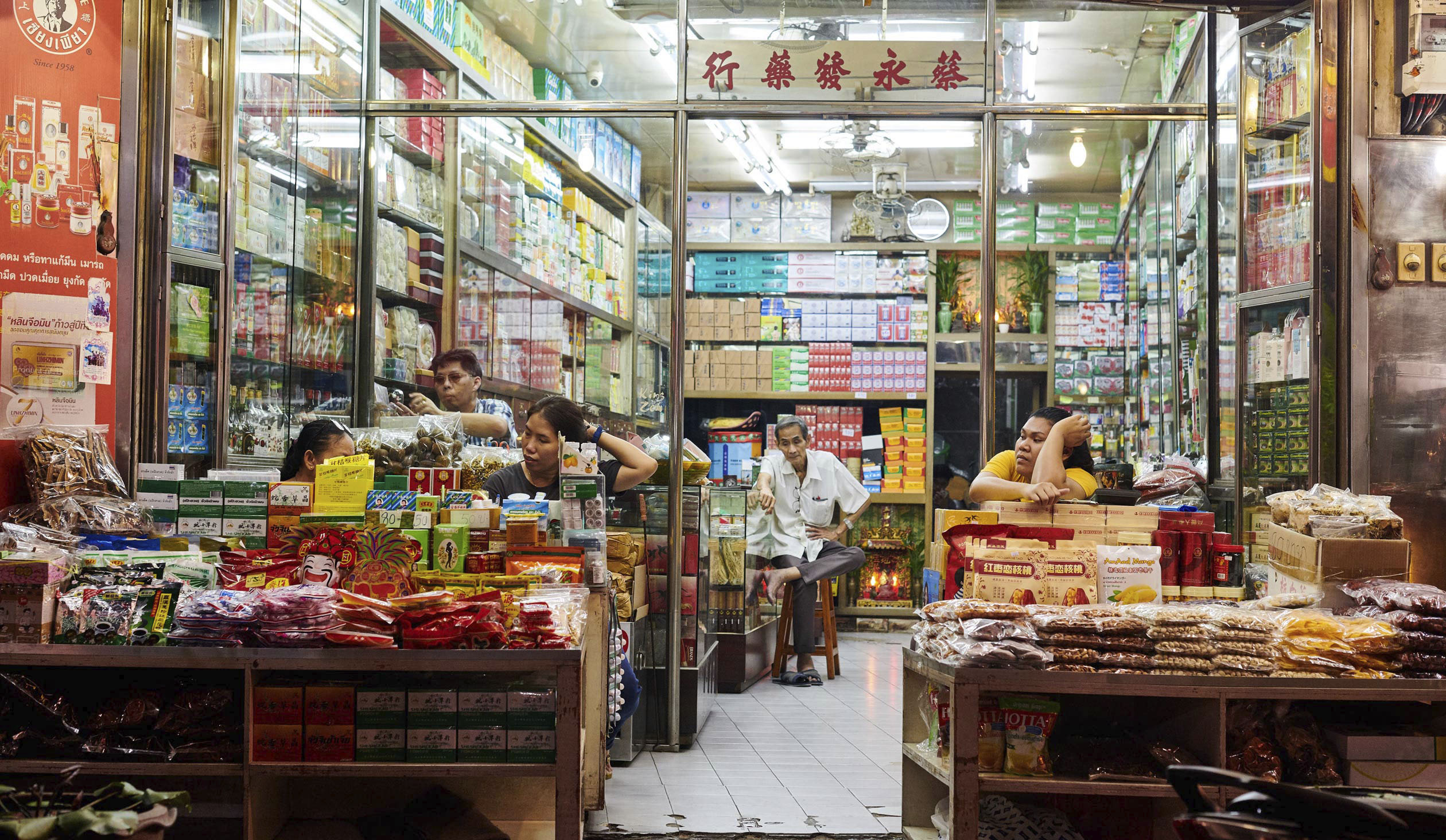 Beitragsbild Chinatown, Chinesische Apotheke fürn Mitarbeiter warten auf kunschaft, Bunt aufenandergestabelte Verpackungen, Reisefotografie
