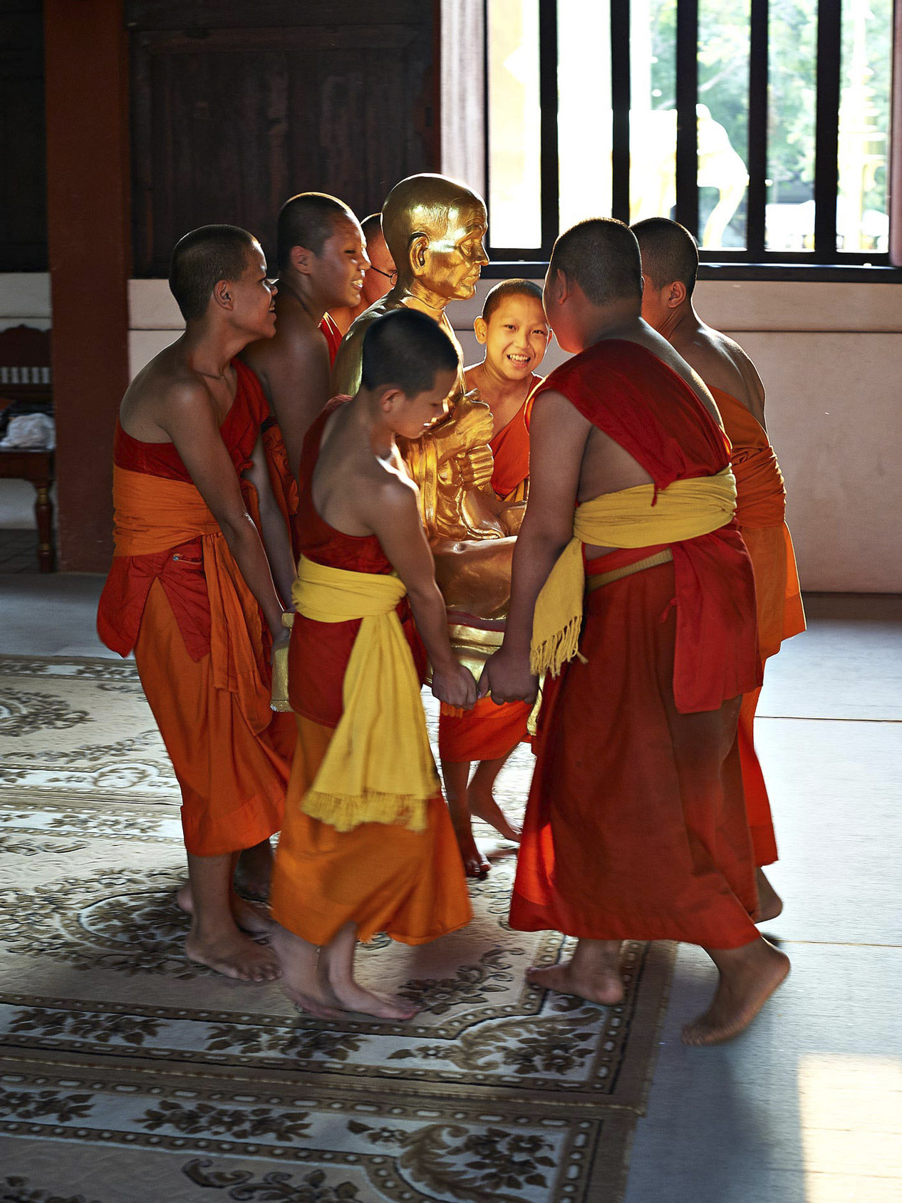 Beitragsbild Corporate, Reisefotografie, Buddhistische Mönche tragen heilige Statue, Kind lacht
